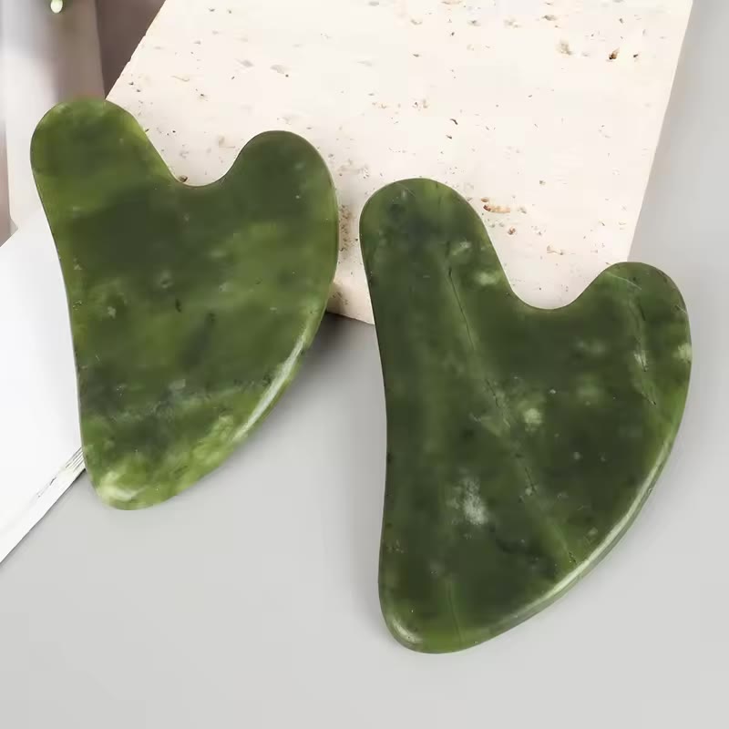 Dos piezas de Gua Sha de jade mostrando el veteado