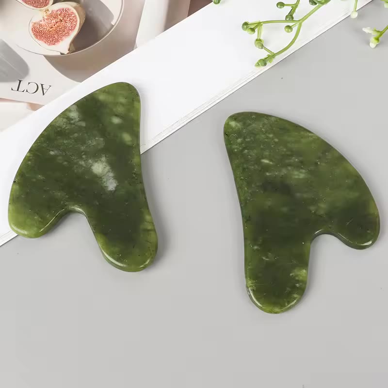Gua Sha de jade sobre superficie clara